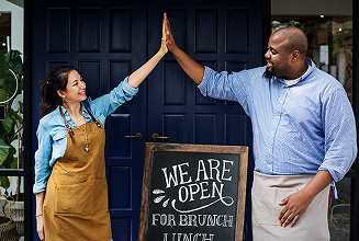 Two people celebrating in front of an open restaurant